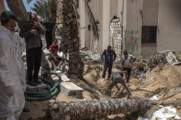 Pessoas e profissionais de saúde desenterram corpos encontrados no Hospital Nasser em Khan Yunis, no sul da Faixa de Gaza, em 23 de abril de 2024       -  (crédito:  AFP)