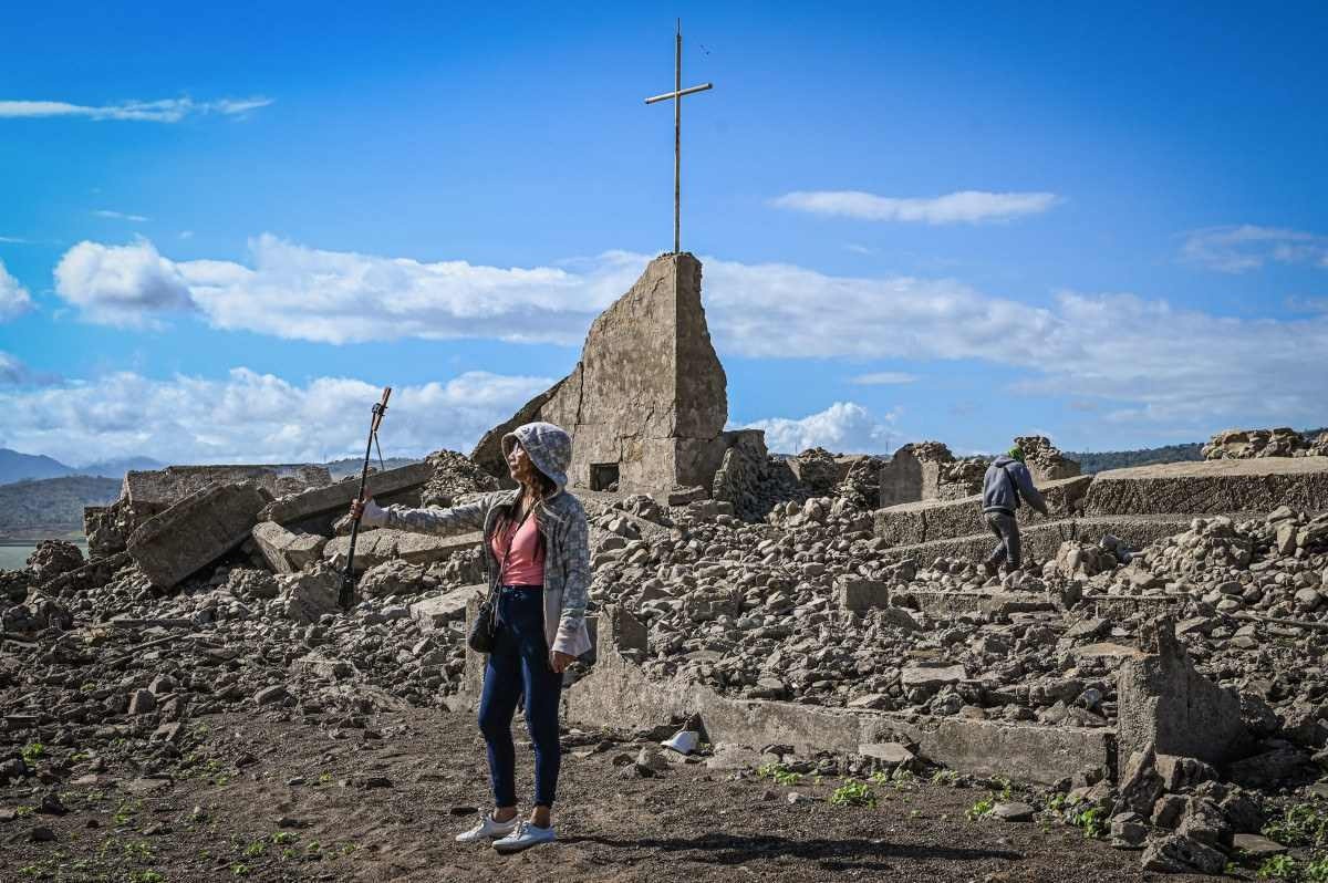  A woman takes a photo near the ruins of a church at the old sunken town of Pantabangan in Nueva Ecija province on April 26, 2024. Remnants of the centuries-old town of Pantabangan reemerged in the northern Philippines after a dam?s water level dropped amid a drought that plagues many parts of the country. (Photo by JAM STA ROSA / AFP) / To go with AFP story Philippines-drought-environment, REPORTAGE by Pam CASTRO
      
