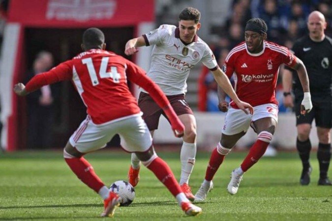 Manchester City's Argentinian striker #19 Julian Alvarez (C) vies with Nottingham Forest's English midfielder #14 Callum Hudson-Odoi (L) during the English Premier League football match between Nottingham Forest and Manchester City at The City Ground in Nottingham, central England, on April 28, 2024. (Photo by JUSTIN TALLIS / AFP) / RESTRICTED TO EDITORIAL USE. No use with unauthorized audio, video, data, fixture lists, club/league logos or 'live' services. Online in-match use limited to 120 images. An additional 40 images may be used in extra time. No video emulation. Social media in-match use limited to 120 images. An additional 40 images may be used in extra time. No use in betting publications, games or single club/league/player publications. / (Photo by JUSTIN TALLIS/AFP via Getty Images)
- (crédito: AFP via Getty Images) Manchester City's Argentinian striker #19 Julian Alvarez (C) vies with Nottingham Forest's English midfielder #14 Callum Hudson-Odoi (L) during the English Premier League football match between Nottingham Forest and Manchester City at The City Ground in Nottingham, central England, on April 28, 2024. (Photo by JUSTIN TALLIS / AFP) / RESTRICTED TO EDITORIAL USE. No use with unauthorized audio, video, data, fixture lists, club/league logos or 'live' services. Online in-match use limited to 120 images. An additional 40 images may be used in extra time. No video emulation. Social media in-match use limited to 120 images. An additional 40 images may be used in extra time. No use in betting publications, games or single club/league/player publications. / (Photo by JUSTIN TALLIS/AFP via Getty Images)
- (crédito: AFP via Getty Images)