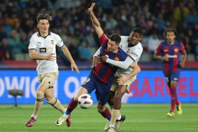 Lewandowski em disputa de bola com jogadores do Valencia - Foto: Lluis Gene/AFP via Getty Images -  (crédito: Lluis Gene/AFP via Getty Images)