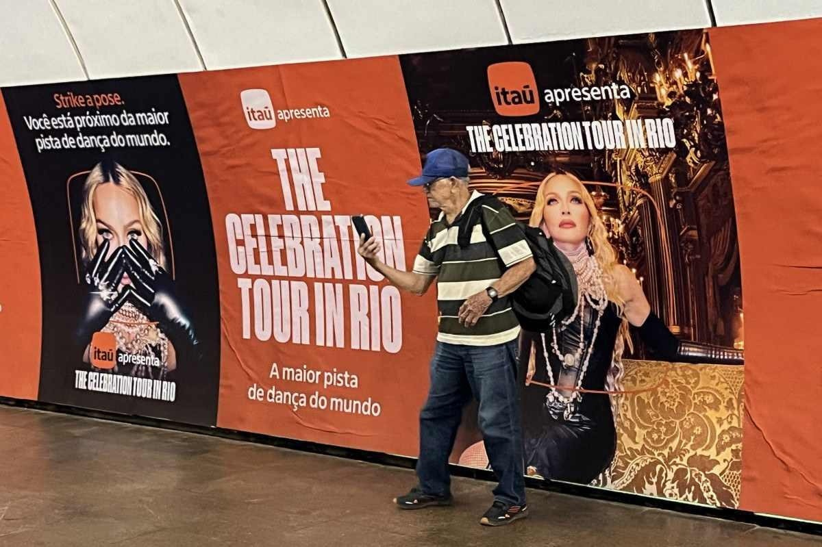 Um homem posa para uma selfie com um anúncio de um show gratuito da estrela pop norte-americana Madonna exibido em uma estação de metrô no bairro de Copacabana. 