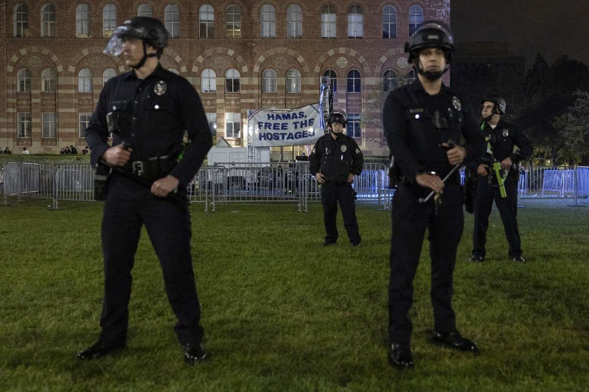 Policiais dos EUA montam guarda em frente a uma faixa que diz 