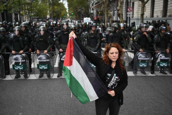  A woman holds a Palestinian flag in front of riot police as members of labor and social organizations march during a May Day (Labor Day) demonstration in Buenos Aires on May 1, 2024. (Photo by Luis ROBAYO / AFP)
      Caption 