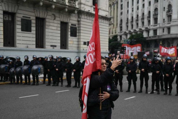  A woman takes a selfie photo in front of riot police as members of labor and social organizations march during a May Day (Labor Day) demonstration in Buenos Aires on May 1, 2024. (Photo by Luis ROBAYO / AFP)
      Caption 