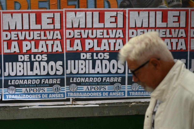  A man walks past posters rejecting Argentine President Javier Milei's government as members of labor and social organizations march during a May Day (Labor Day) demonstration in Buenos Aires on May 1, 2024. (Photo by Luis ROBAYO / AFP)
      Caption 