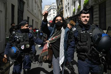 Manifestante é escoltado por policiais franceses durante repressão a protesto na Sciences Po, em Paris:  -  (crédito: Miguel Medina/AFP)