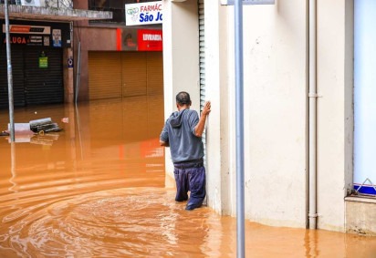 Homem tenta atravessar as ruas do centro de Porto Alegre tomadas pelas água dos Guaíba -  (crédito: Gustavo Mansur/Palácio Piratini)