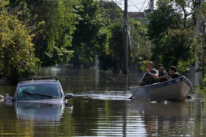 Moradores se movem em barcos após inundações devido a fortes chuvas em Porto Alegre -  (crédito: Nélson Almeida/AFP)