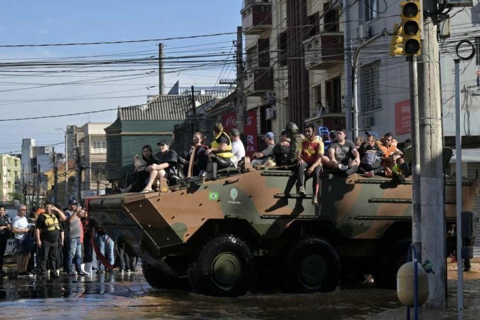  People are taken out of a flooded area in a military personnel carrier following floodings due to heavy rains in Porto Alegre, Rio Grande do Sul state, Brazil on May 6, 2024. From top to bottom, rescuers scour buildings in Porto Alegre for inhabitants stuck in apartments or on rooftops as unprecedented flooding killed at least 78 people in the southern state, with dozens missing and some 115,000 forced to leave their homes. (Photo by NELSON ALMEIDA / AFP)
       -  (crédito:  AFP)