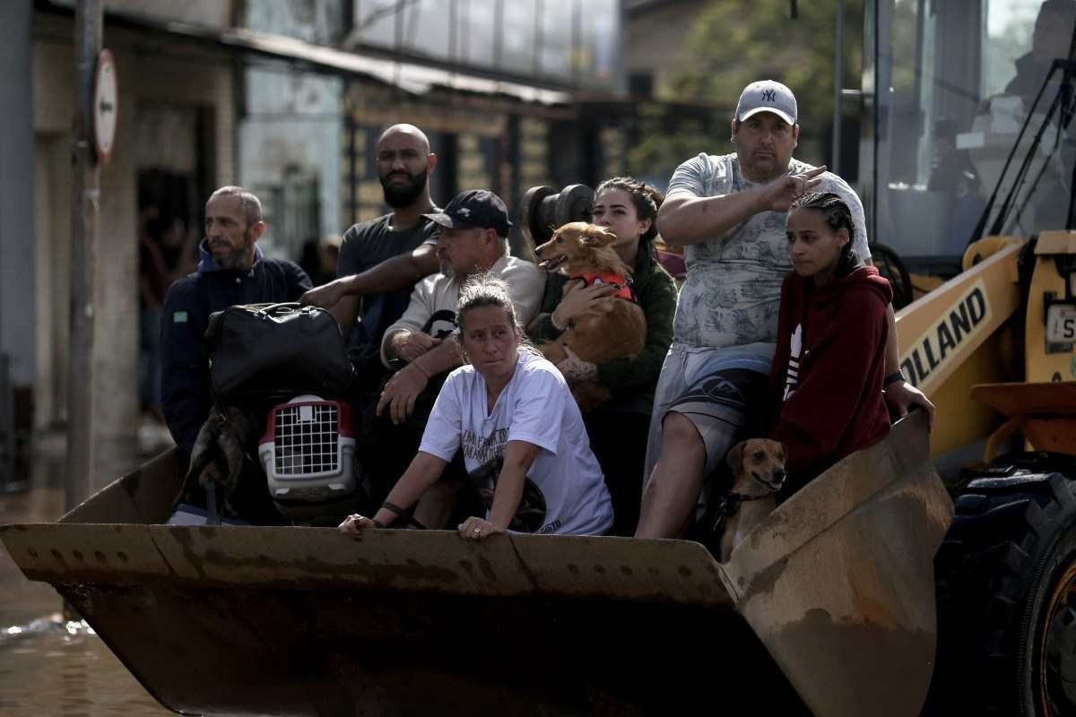 Pessoas são transportadas em retroescavadeira após serem resgatadas no bairro Sarandi, em Porto Alegre, Rio Grande do Sul, Brasil, em 5 de maio de 2024      