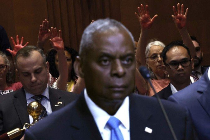 Manifestantes mostram mãos cobertas de tinta vermelha durante audiência de Loyd Austin no Congresso 