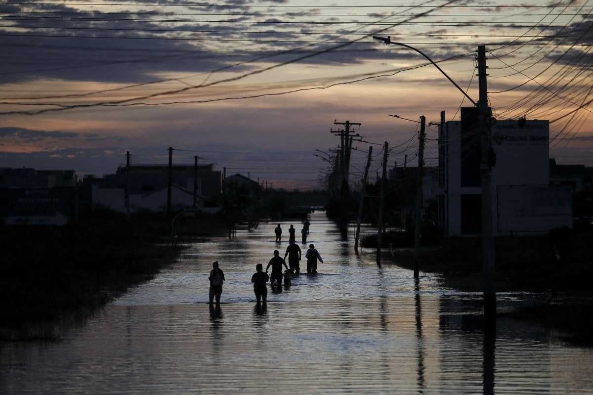 Pessoas caminham por uma rua inundada de Eldorado do Sul, no Rio Grande do Sul      