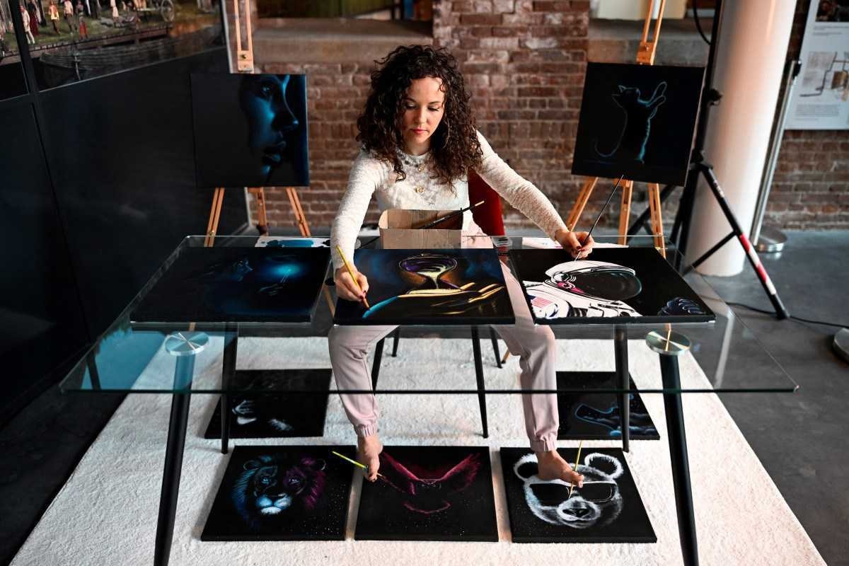 A artista que usa suas mãos e pés para pintar dez quadros simultaneamente