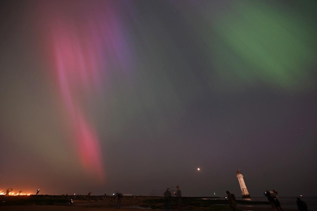As pessoas se reúnem para observar a Aurora Boreal em New Brighton, no noroeste da Inglaterra, no final de 10 de maio de 2024