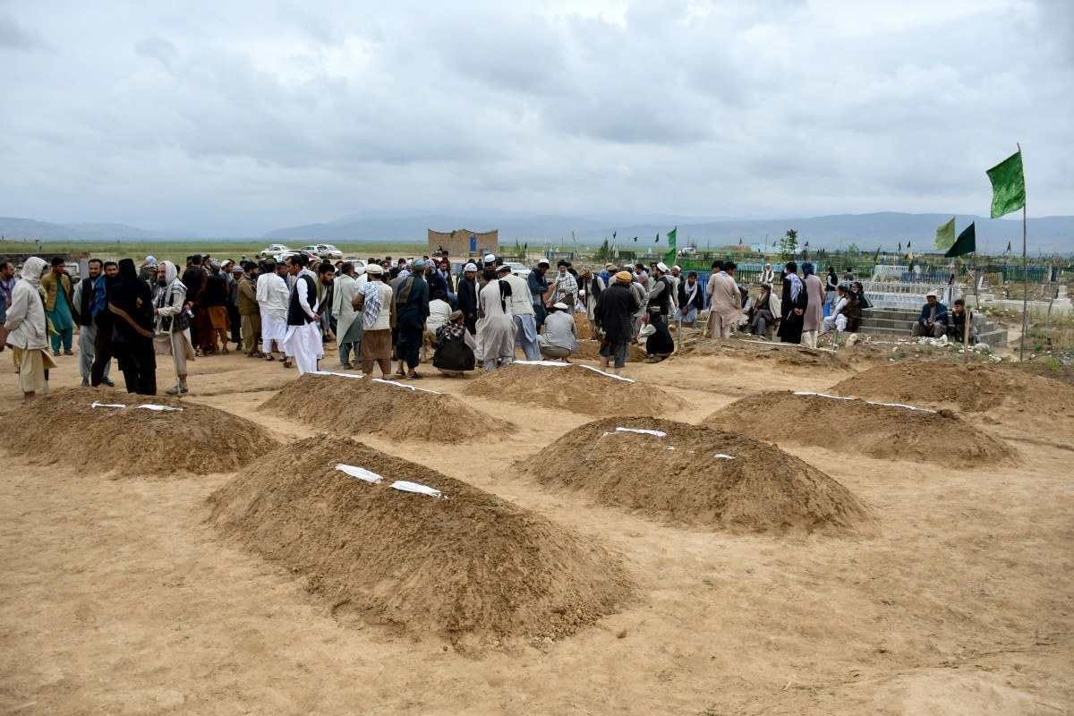 Parentes afegãos oferecem orações durante uma cerimônia fúnebre, perto dos túmulos das vítimas que perderam a vida após enchentes repentinas após fortes chuvas em um vilarejo no distrito de Baghlan-e-Markazi, na província de Baghlan, em 11 de maio de 2024