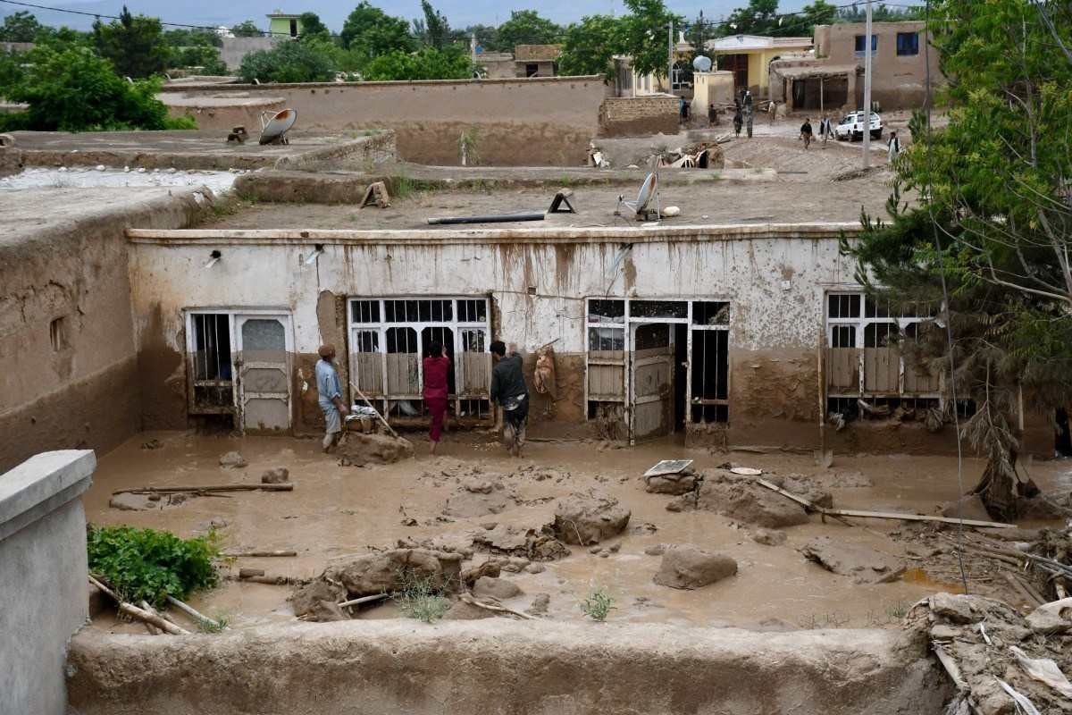 Homens afegãos limpam a lama de uma casa após enchentes repentinas após fortes chuvas em um vilarejo no distrito de Baghlan-e-Markazi, na província de Baghlan, em 11 de maio de 2024
