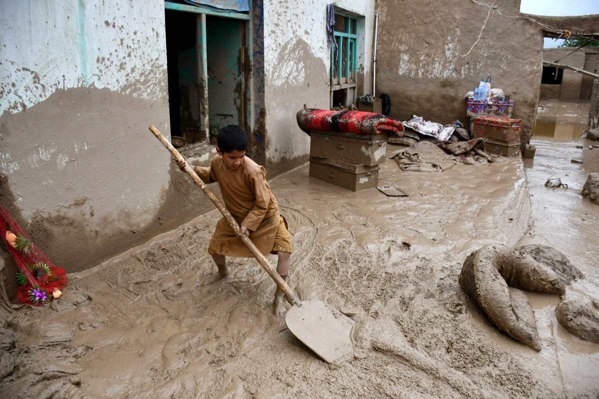 Um menino afegão remove lama do pátio de uma casa após enchentes repentinas após fortes chuvas em um vilarejo no distrito de Baghlan-e-Markazi, na província de Baghlan, em 11 de maio de 2024. 