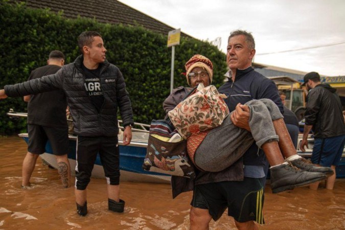 Idosa em cadeira de rodas sendo resgatada em Porto Alegre -  (crédito: NELSON ALMEIDA/AFP via Getty Images)