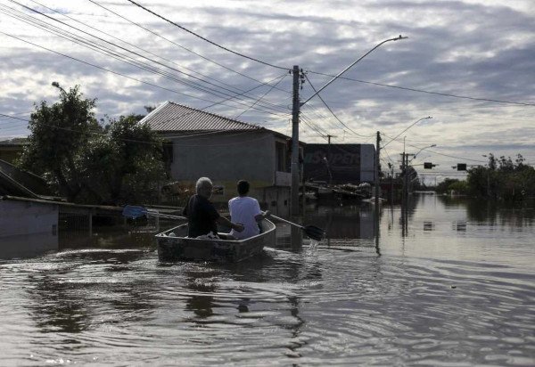  Men paddle a boat through a flooded street in the Rio Branco neighborhood to voluntary transport residents in Canoas, Rio Grande do Sul state, Brazil, on May 17, 2024. More than 600,000 people have been displaced by the heavy rain, flooding and mudslides that have ravaged the south of the state of Rio Grande do Sul for around two weeks. (Photo by Anselmo Cunha / AFP)
       -  (crédito:  Anselmo Cunha / AFP)
