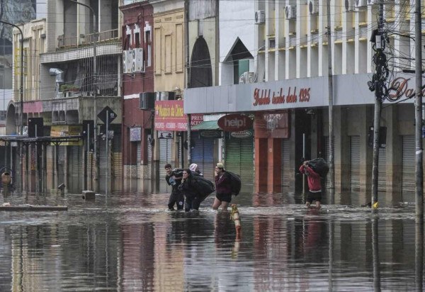 Pessoas caminham por rua inundada: risco de infecção -  (crédito: NELSON ALMEIDA / AFP)