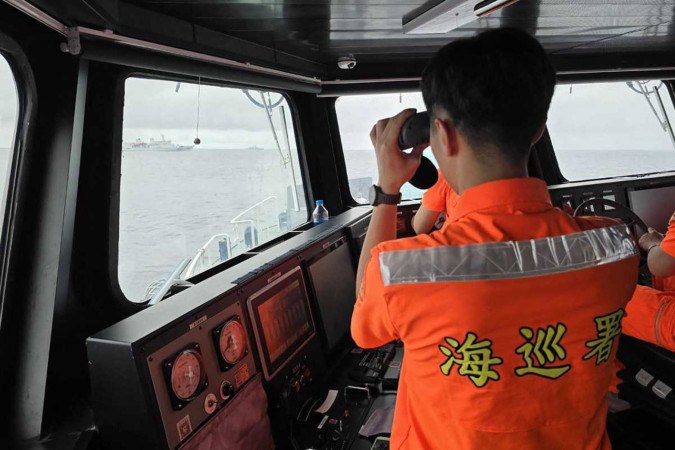 Oficial da Guarda Costeira de Taiwan monitora navio de guerra chinês (E), ao norte da Ilha de Pengjja  -  (crédito: Guarda Costeira de Taiwan/AFP)