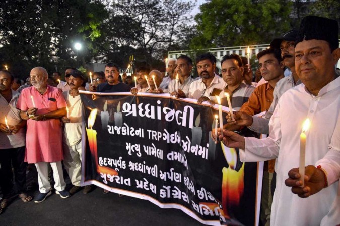 Pessoas participam de uma vigília à luz de velas para prestar homenagem às pessoas que perderam a vida após um incêndio em um parque de diversões em Rajkot, no estado indiano de Gujarat       -  (crédito:  AFP)