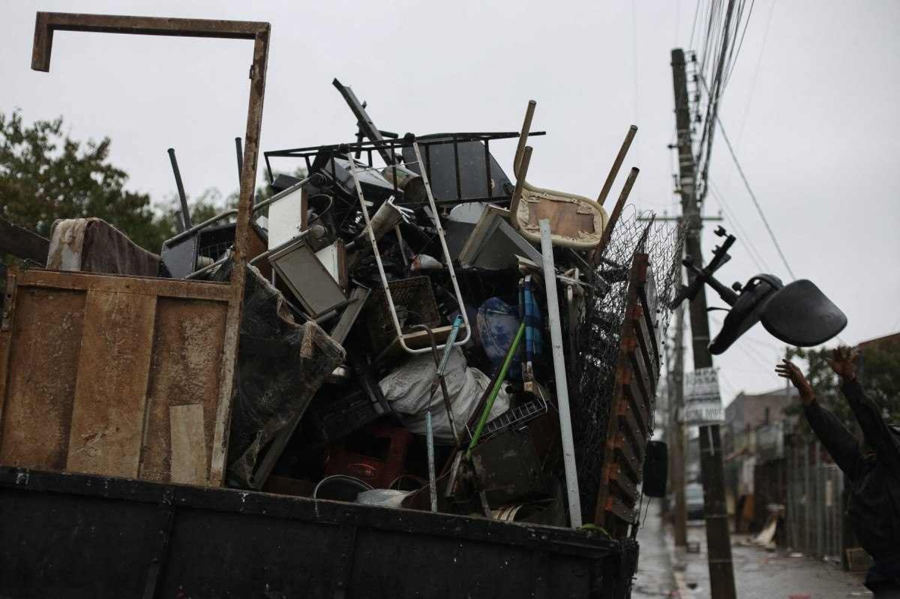  A man throws a chair into a truck carrying rubble from houses affected by the flood in the Sarandi neighborhood, one of the hardest hit by the heavy rains in Porto Alegre, Rio Grande do Sul state, Brazil, on May 27, 2024. Cities and rural areas alike in Rio Grande do Sul have been hit for weeks by an unprecedented climate disaster of torrential rains and deadly flooding. More than half a million people have fled their homes, and authorities have been unable to fully assess the extent of the damage. (Photo by Anselmo Cunha / AFP)       Caption 