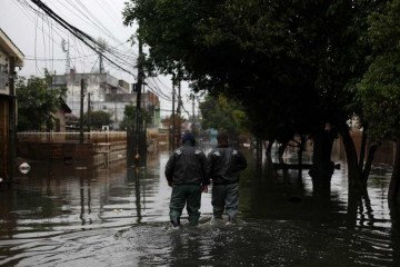  Men wade through a flooded street in the Sarandi neighborhood, one of the hardest hit by the heavy rains in Porto Alegre, Rio Grande do Sul state, Brazil, on May 27, 2024. Cities and rural areas alike in Rio Grande do Sul have been hit for weeks by an unprecedented climate disaster of torrential rains and deadly flooding. More than half a million people have fled their homes, and authorities have been unable to fully assess the extent of the damage. (Photo by Anselmo Cunha / AFP)
      Caption  -  (crédito:  ANSELMO CUNHA/AFP)