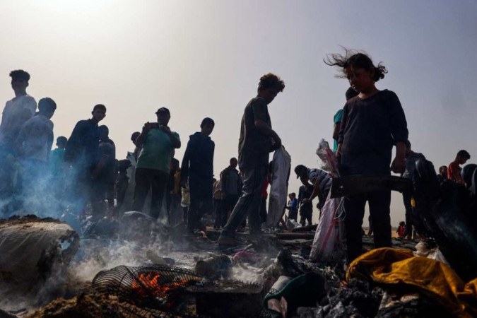 Palestinos se reúnem no local de um ataque israelense em uma área de campo que abriga pessoas deslocadas internamente em Rafah em 27 de maio de 2024, em meio a batalhas contínuas entre Israel e o grupo militante palestino Hamas.       -  (crédito: Eyad BABA / AFP)