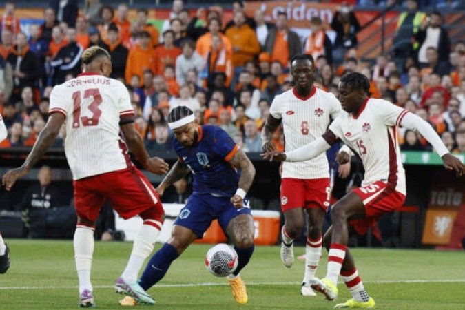 Memphis Depay em disputa de bola com jogadores do Canadá - Foto: Koen van Weel/AFP via Getty Images -  (crédito: Koen van Weel/AFP via Getty Images)