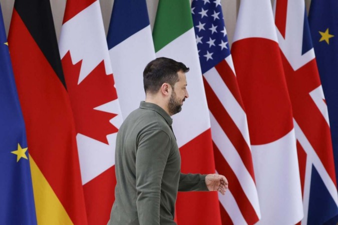 O presidente ucraniano, Volodymyr Zelensky, caminha em frente às bandeiras ao chegar à cúpula do G7