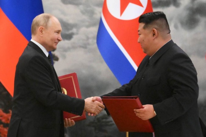 Vladimir Putin (E) cumprimenta Kim Jong-un depois de cerimônia de assinatura de acordos bilaterais, em Pyongyang  -  (crédito: Kristina Kormilitsyna/AFP)