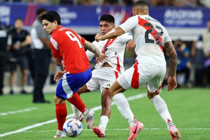 O chileno Dávila (de vermelho) recebe marcação dupla dos peruanos Quispe e Callens e tenta levar a melhor e partir para o ataque  -  (crédito: Foto: Aric Becker/AFP via Getty Images)