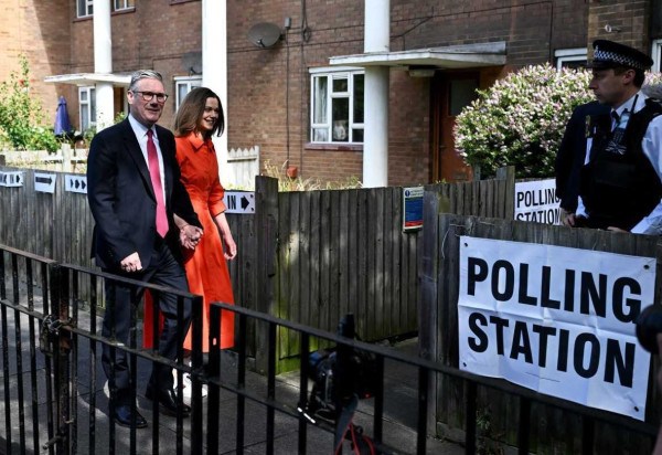 Keir Starmer, líder do Partido Trabalhista, chega acompanhado da mulher, Victoria, a um centro de votação, em em Londres -  (crédito: Paul Ellis/AFP)