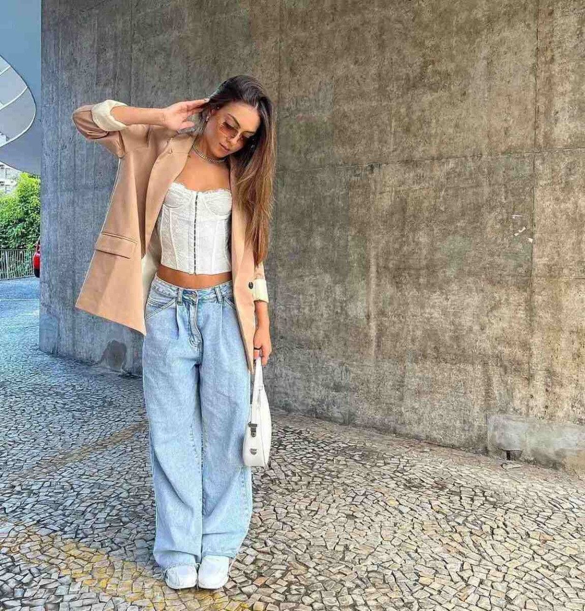 A combinação da terceira peça, como um blazer, com a calça larga de cintura baixa, complementa o visual e garante um caráter menos informal para o look