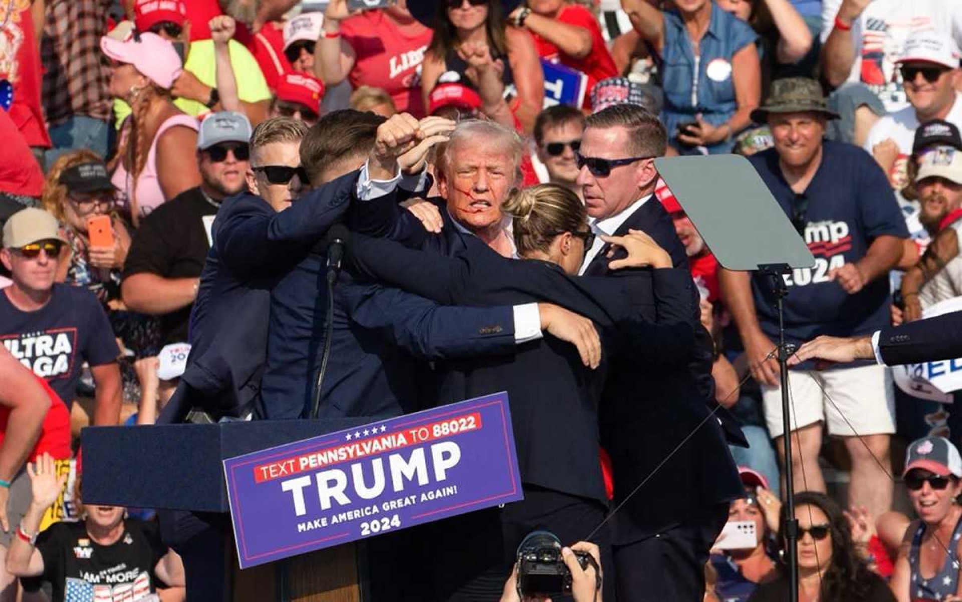  Republican candidate Donald Trump is seen with what appears to be blood on his face surrounded by secret service agents as he is taken off the stage at a campaign event at Butler Farm Show Inc. in Butler, Pennsylvania, July 13, 2024. Republican candidate Donald Trump was evacuated from the stage at todays rally after what sounded like shots rang out at the event in Pennsylvania, according to AFP. The former US president was seen with blood on his right ear as he was surrounded by security agents, who hustled him off the stage as he pumped his first to the crowd. Trump was bundled into an SUV and driven away. (Photo by Rebecca DROKE / AFP)       