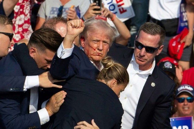 O candidato republicano Donald Trump é visto com sangue no rosto cercado por agentes do serviço secreto ao ser retirado do palco em um evento de campanha no Butler Farm Show Inc. em Butler, Pensilvânia, 13 de julho de 2024 -  (crédito: Rebecca DROKE / AFP)