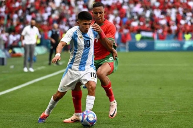  Argentina's midfielder #10 Thiago Almada outflanks Morocco's forward #09 Soufiane Rahimi in the men's group B football match between Argentina and Morocco during the Paris 2024 Olympic Games at the Geoffroy-Guichard Stadium in Saint-Etienne on July 24, 2024. (Photo by Arnaud FINISTRE / AFP) (Photo by ARNAUD FINISTRE/AFP via Getty Images)
     -  (crédito:  AFP via Getty Images)