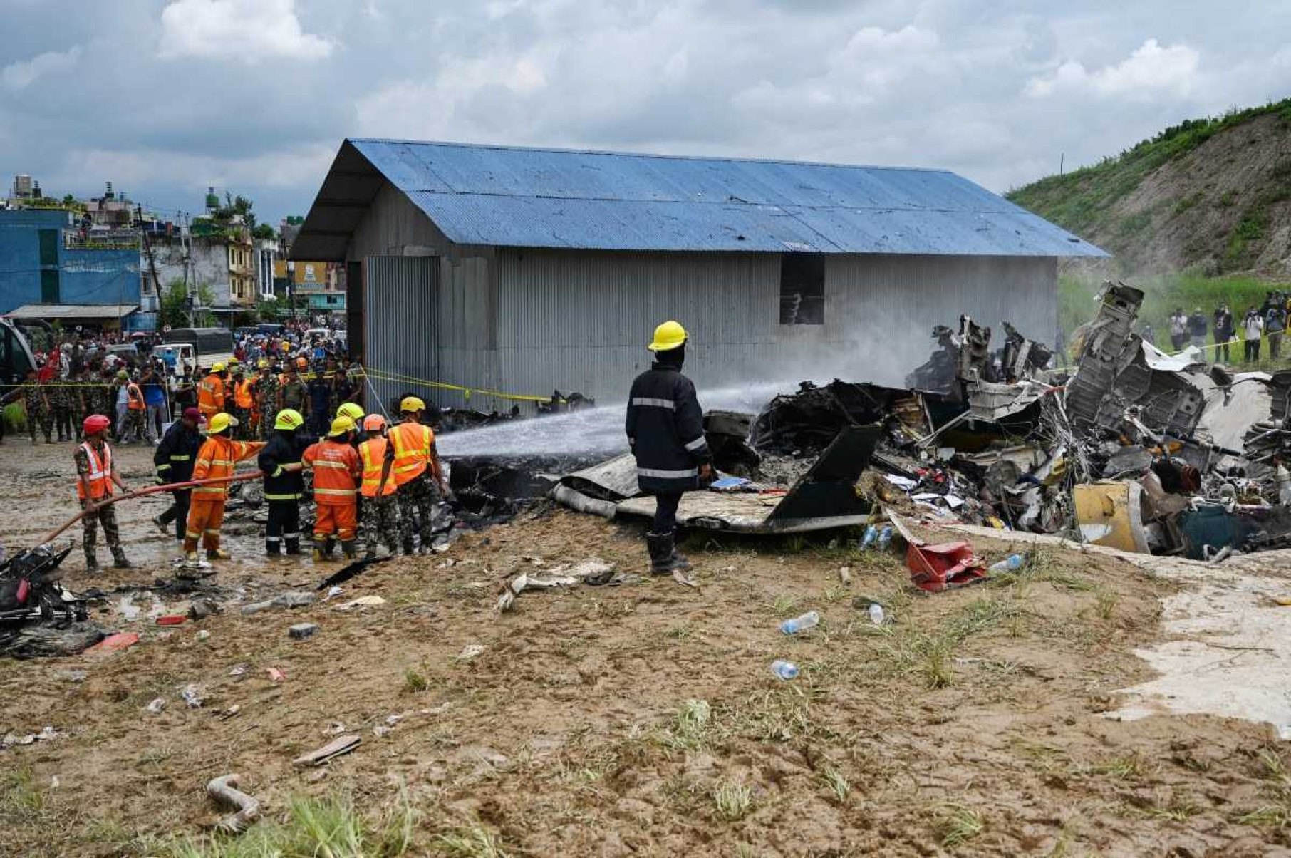 Bombeiros tentam apagar um incêndio que eclodiu nos destroços do voo da Saurya Airlines depois que ele caiu durante a decolagem no Aeroporto Internacional de Tribhuvan, em Katmandu, em 24 de julho de 2024      