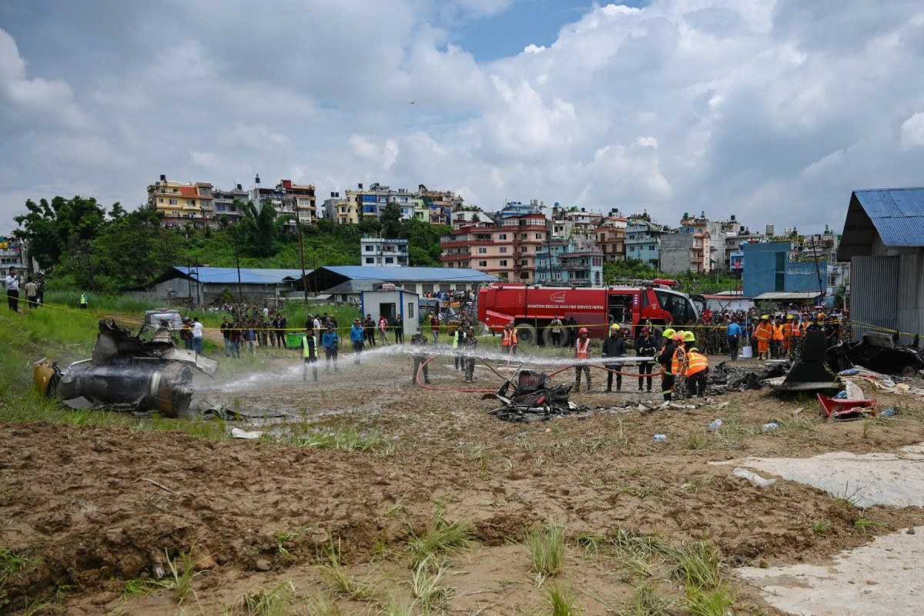 Bombeiros tentam apagar um incêndio que eclodiu nos destroços do voo da Saurya Airlines depois que ele caiu durante a decolagem no Aeroporto Internacional de Tribhuvan, em Katmandu, em 24 de julho de 2024      