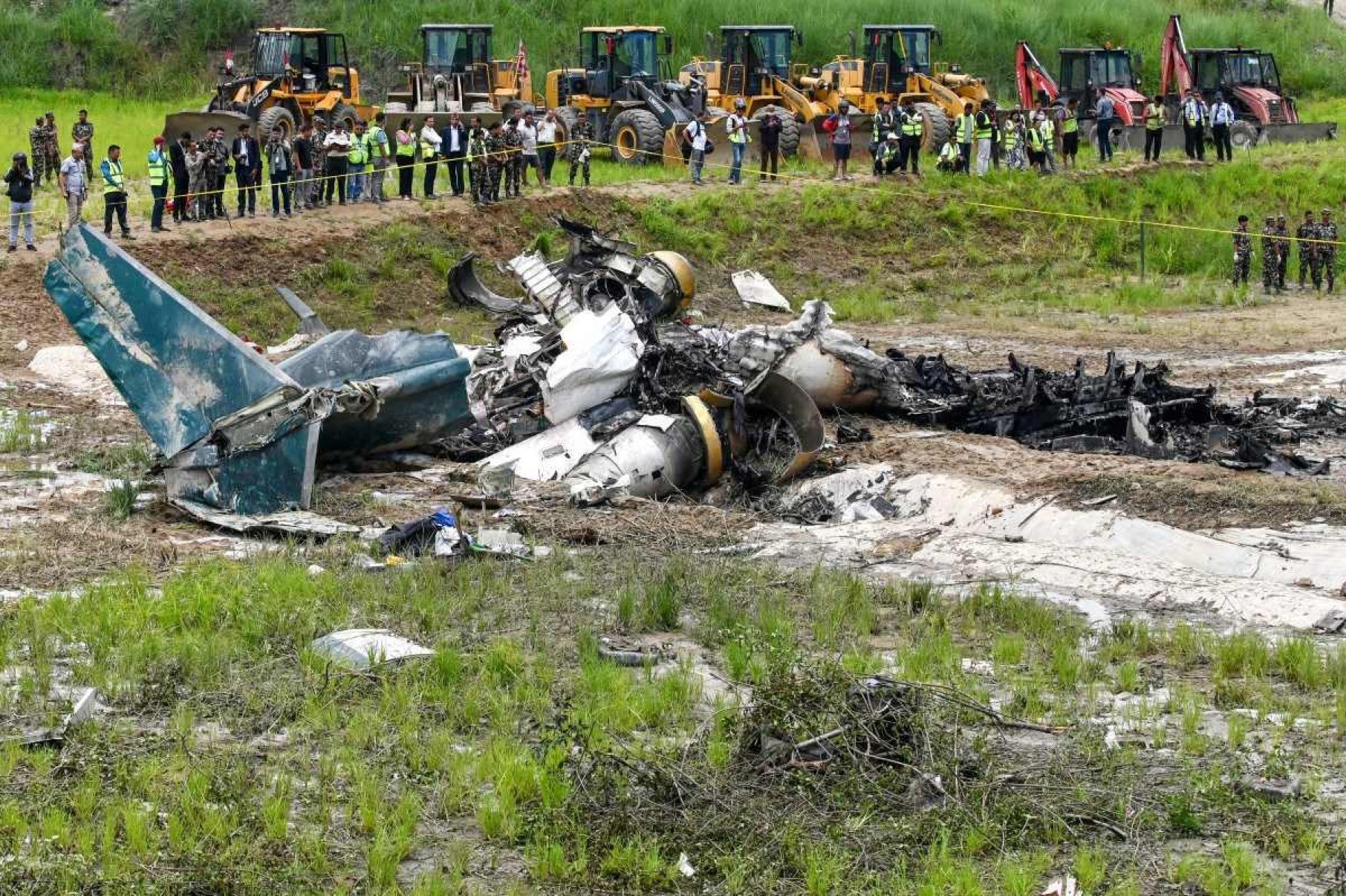 Militares do exército e outros oficiais ficam ao redor dos destroços de um voo da Saurya Airlines depois que ele caiu durante a decolagem no Aeroporto Internacional de Tribhuvan, em Katmandu, em 24 de julho de 2024      