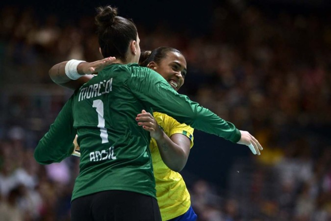 A pivô do Brasil Tamires Araujo comemora com a goleira 01 Gabriela Moreschi durante a partida de handebol       -  (crédito: ARIS MESSINIS / AFP)