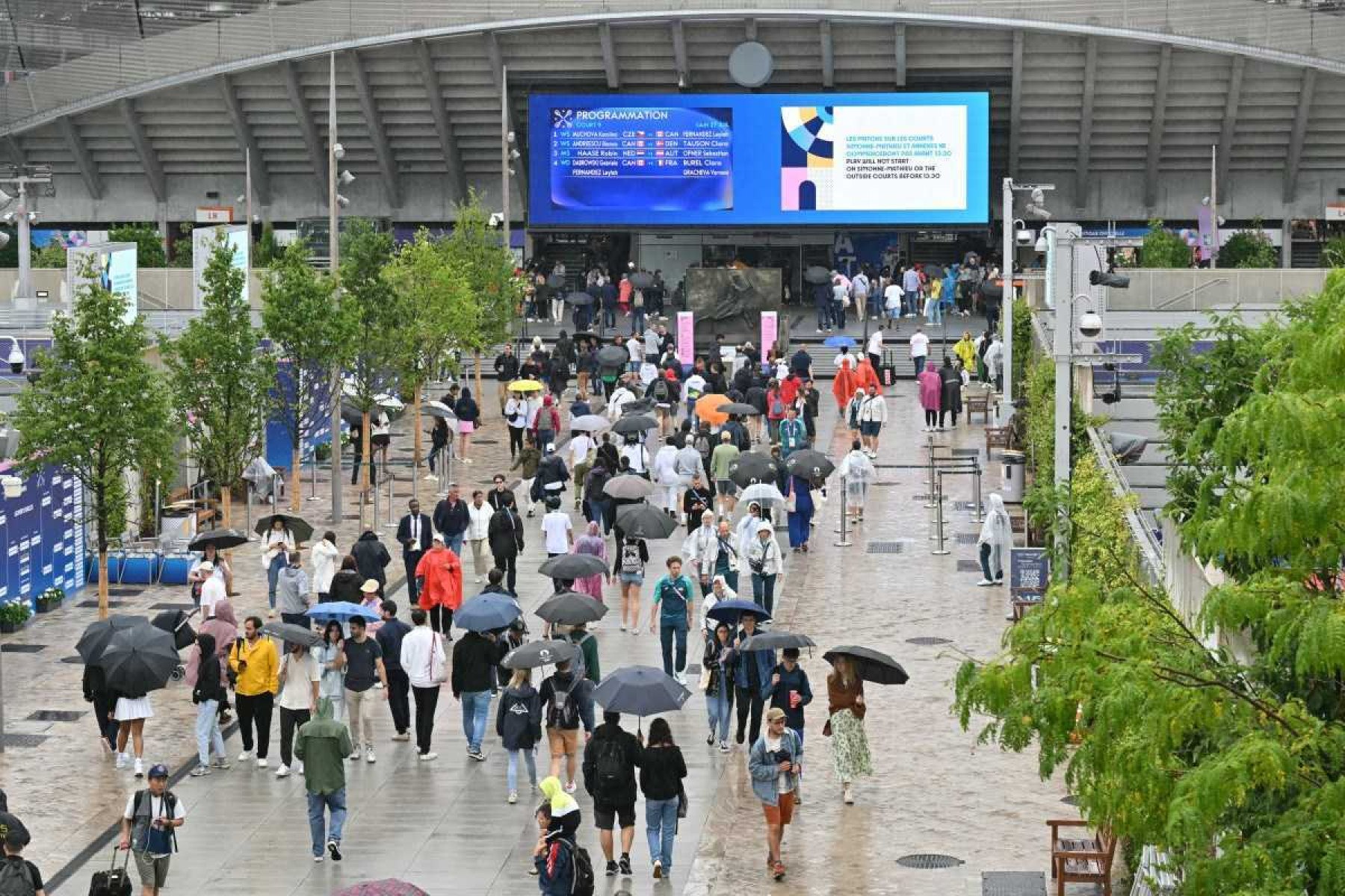 Espectadores se protegem da chuva enquanto a chuva atrasa o início dos jogos nas quadras externas do Estádio Roland-Garros dos Jogos Olímpicos Paris 2024, em Paris, no dia 27 de julho de 2024.   