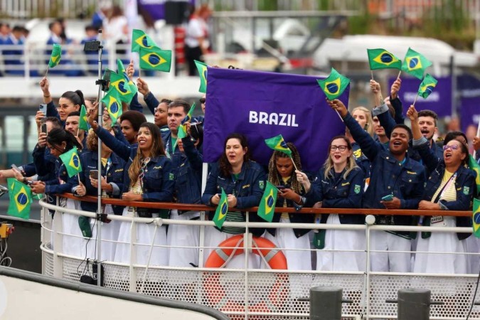 Atletas da Seleção Brasileira agitam bandeiras nacionais em um barco antes da cerimônia de abertura dos Jogos Olímpicos Paris 2024, em 26 de julho de 2024, em Paris, França.  -  (crédito: Michael Reaves/POOL/AFP)