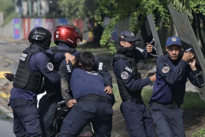     Polícia carrega colega ferido durante confrontos, enquanto outros dois fornecem cobertura