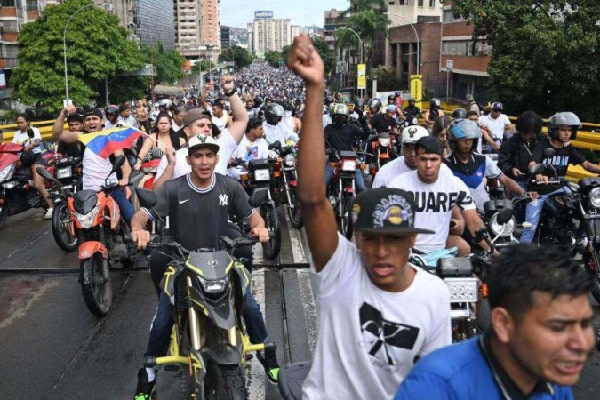 Um oponente do governo do presidente venezuelano Nicolás Maduro queima cartazes da campanha do atual presidente durante um protesto em Petare -  (crédito: Getty Images)