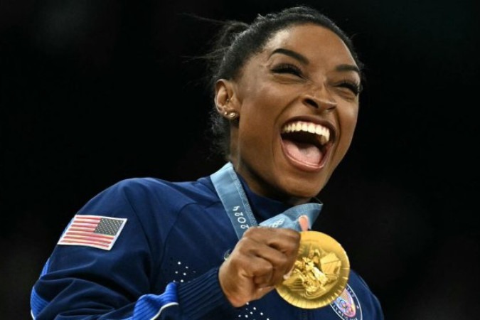 Simone Biles comemora mais um ouro com a equipe de ginástica dos EUA -  (crédito: Foto: Lionel Bonaventure/AFP via Getty Images)