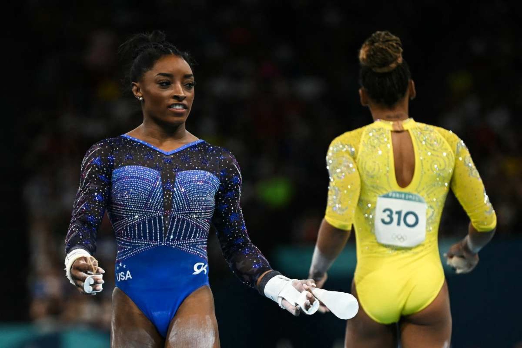  US Simone Bile (L) and Brazils Rebeca Andrade compete in the artistic gymnastics womens all around final during the Paris 2024 Olympic Games at the Bercy Arena in Paris, on August 1, 2024. (Photo by Paul ELLIS / AFP)       