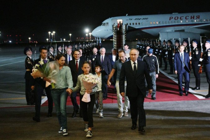 O presidente Vladimir Putin (D) deu as boas-vindas a um grupo de cidadãos russos no aeroporto de Vnukovo, em Moscou