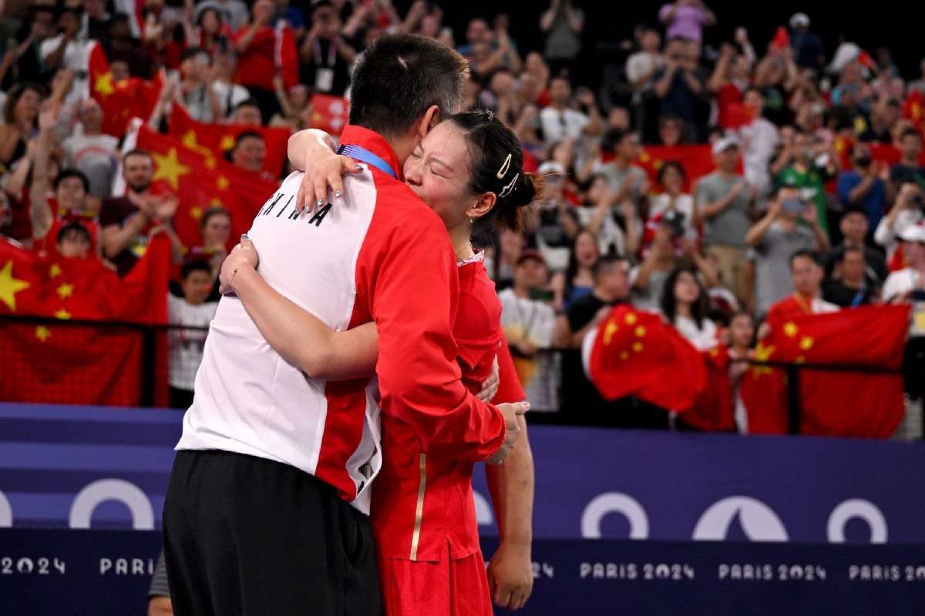 Huang Ya Qiong abraça seu treinador enquanto comemora a vitória na final do badminton de duplas mistas contra a Coreia do Sul   